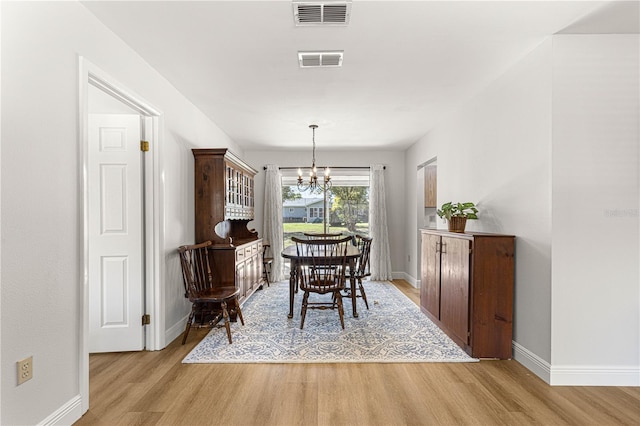 dining area with light wood-style floors, visible vents, and a notable chandelier