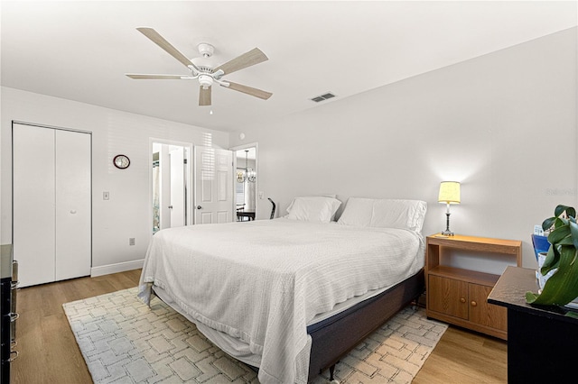 bedroom featuring light wood finished floors, baseboards, visible vents, and a ceiling fan