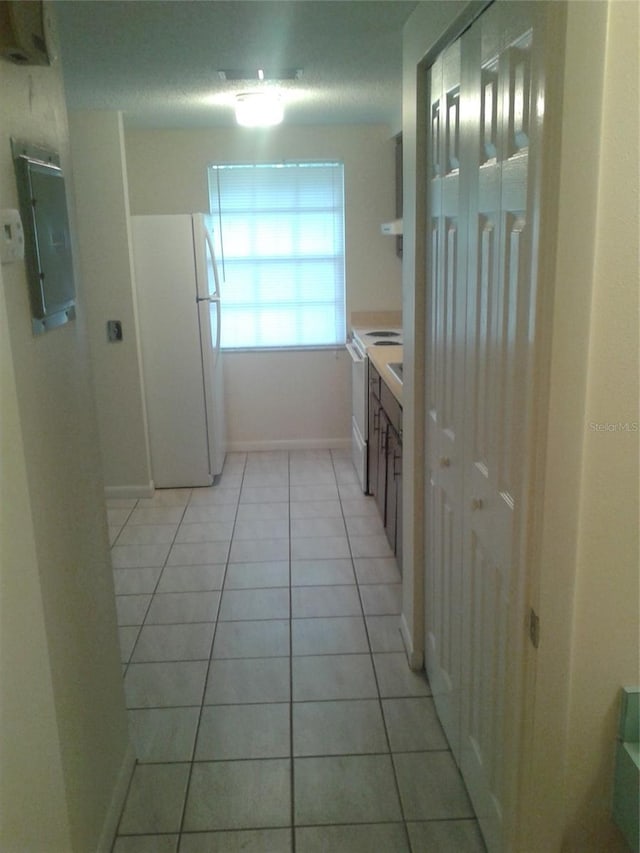 interior space with a closet, electric panel, baseboards, and tile patterned floors