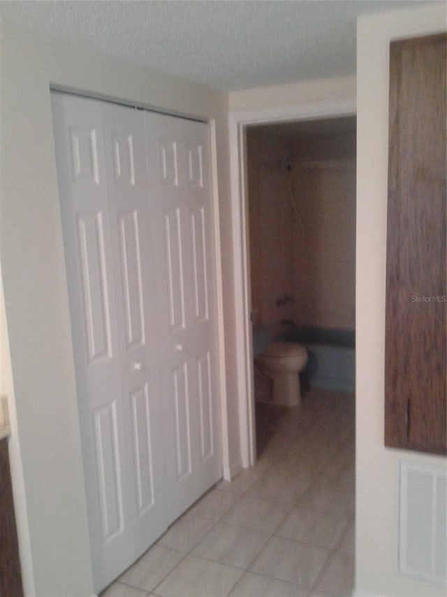 bathroom with tile patterned flooring, visible vents, and toilet