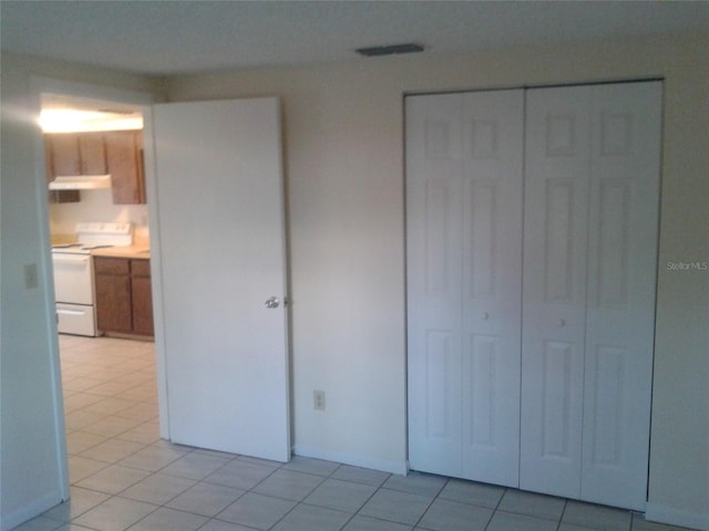 unfurnished bedroom with a closet, light tile patterned flooring, and visible vents