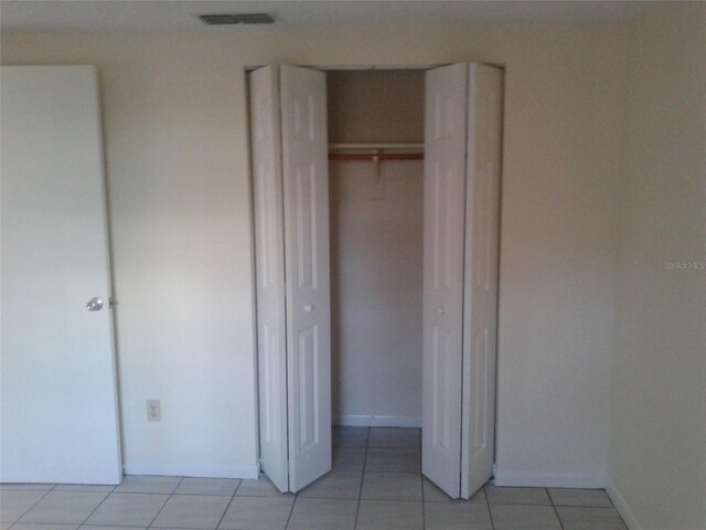 unfurnished bedroom with light tile patterned floors, baseboards, visible vents, and a closet