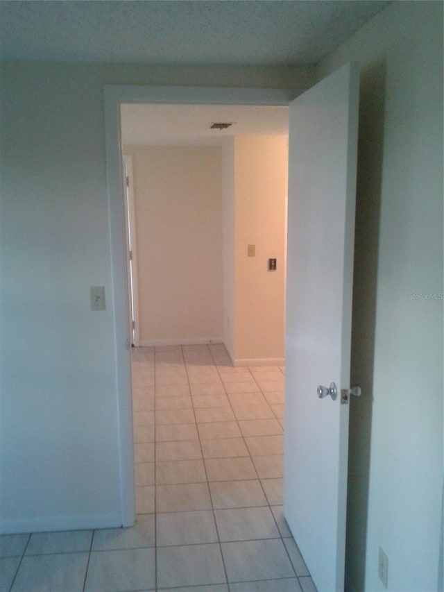 hall with light tile patterned flooring, visible vents, and baseboards