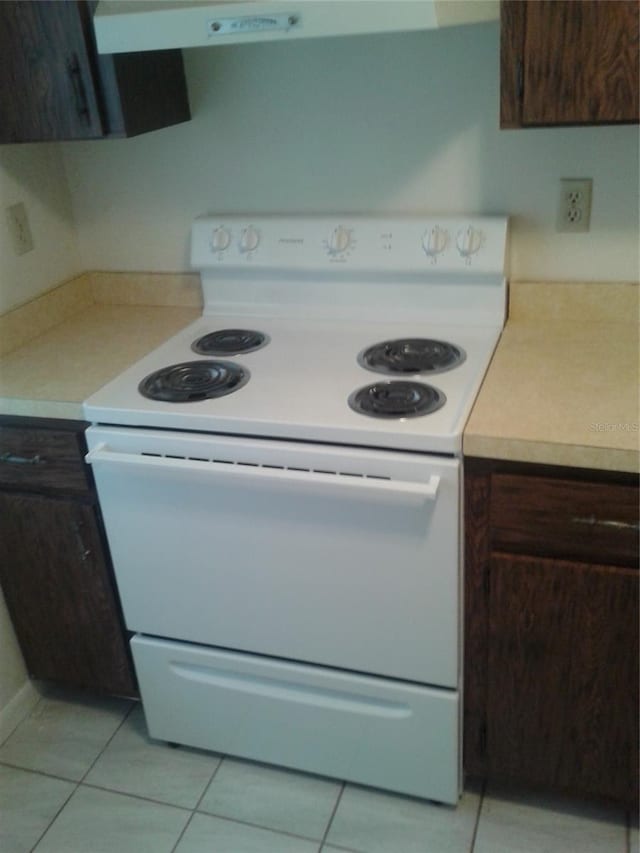 kitchen featuring light tile patterned flooring, light countertops, dark brown cabinetry, and white range with electric cooktop