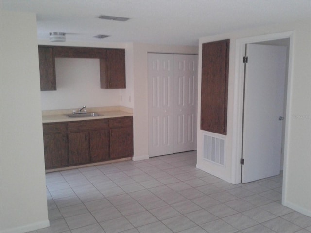 kitchen with light tile patterned floors, light countertops, visible vents, a sink, and dark brown cabinetry