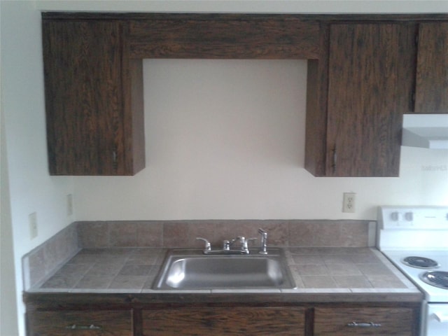 kitchen with tile countertops, electric range, a sink, dark brown cabinetry, and extractor fan