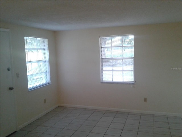 empty room with baseboards and light tile patterned flooring