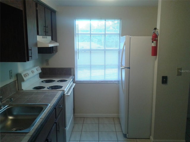 kitchen with tile countertops, light tile patterned floors, under cabinet range hood, white appliances, and a sink