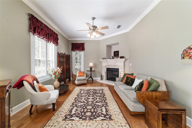 living room featuring baseboards, visible vents, a glass covered fireplace, wood finished floors, and crown molding