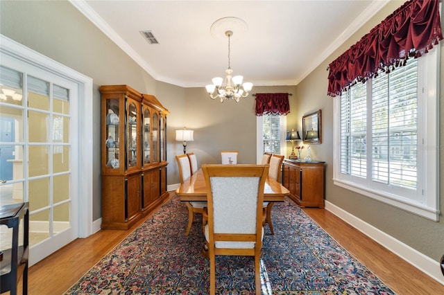 dining space with ornamental molding, light wood-style flooring, visible vents, and baseboards