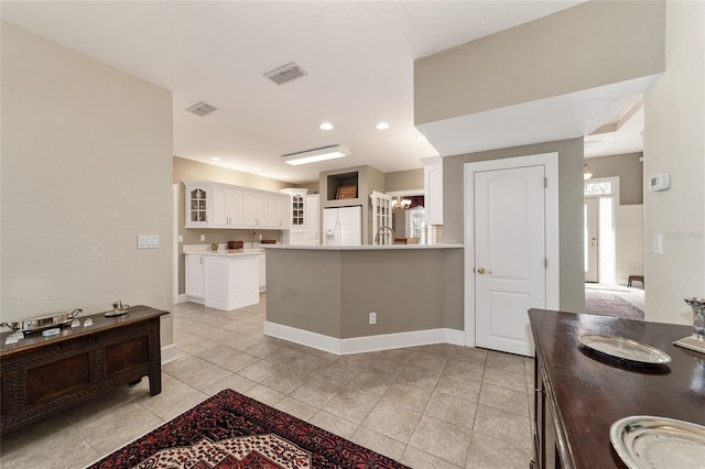 kitchen featuring visible vents, glass insert cabinets, white cabinets, white fridge with ice dispenser, and baseboards