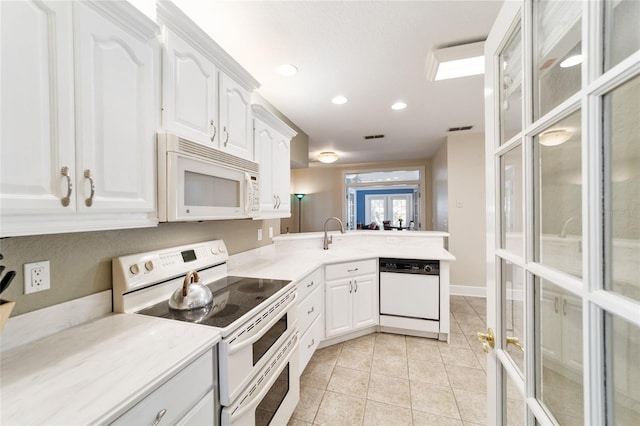 kitchen featuring white appliances, light tile patterned floors, visible vents, a peninsula, and white cabinetry