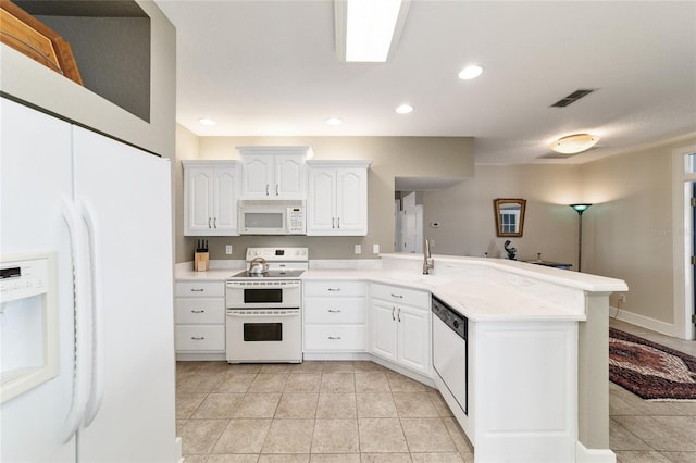 kitchen with white appliances, a peninsula, light countertops, white cabinetry, and light tile patterned flooring