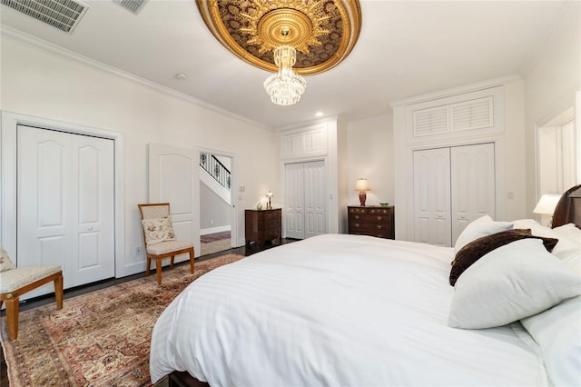 bedroom with visible vents, baseboards, an inviting chandelier, crown molding, and multiple closets