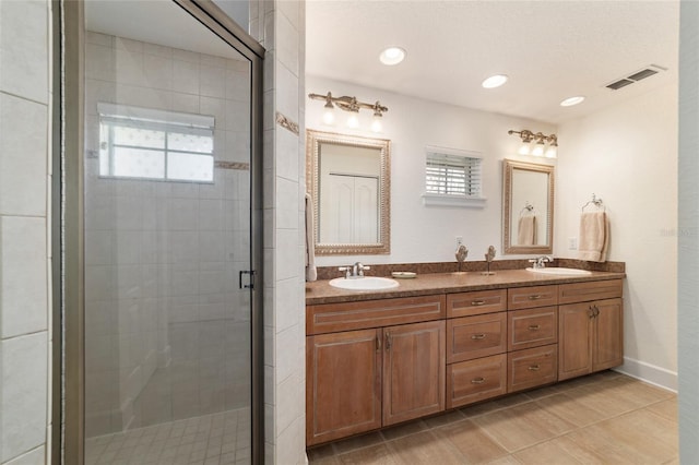 full bathroom featuring double vanity, a stall shower, a sink, and visible vents