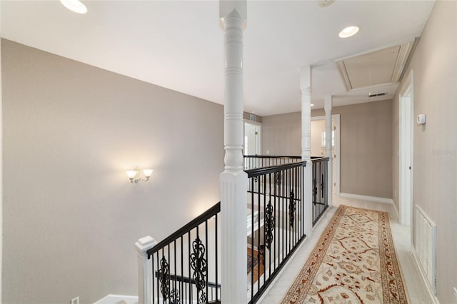 hall featuring attic access, visible vents, baseboards, and an upstairs landing