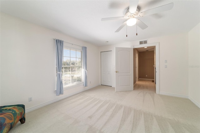 unfurnished bedroom featuring baseboards, a ceiling fan, visible vents, and light colored carpet