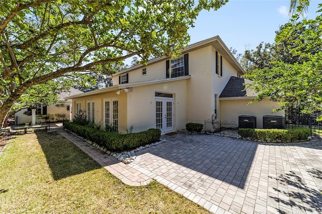 back of house featuring french doors, central AC unit, and stucco siding