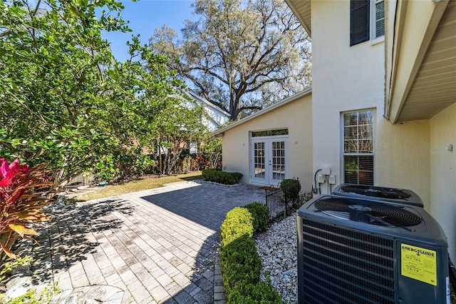 view of patio / terrace featuring french doors, central AC unit, and fence