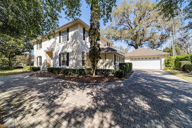 view of front of home featuring a garage, an outdoor structure, and stucco siding