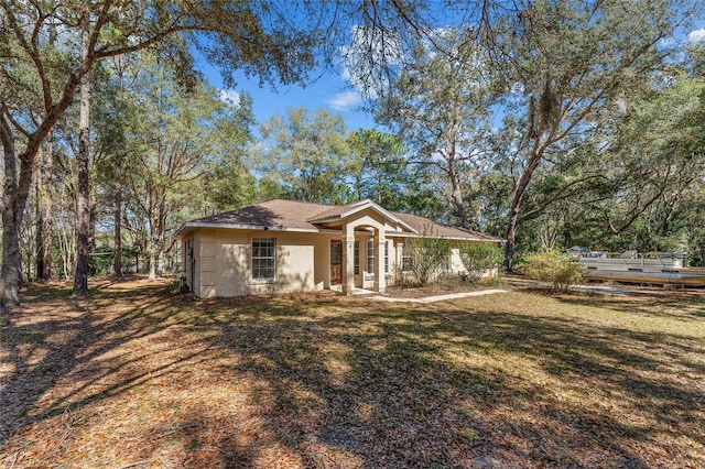 ranch-style house with stucco siding and a front yard