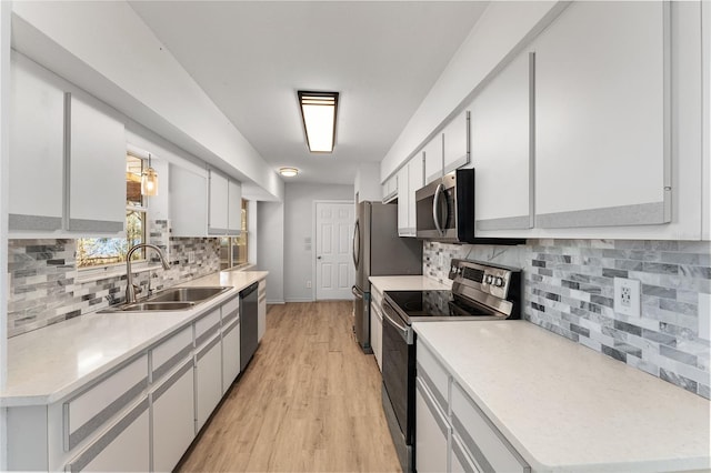 kitchen with stainless steel appliances, a sink, light countertops, and white cabinets