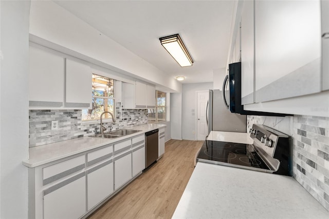 kitchen with light countertops, appliances with stainless steel finishes, a sink, and white cabinets