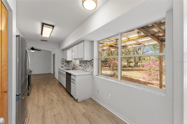 kitchen with a sink, white cabinetry, light countertops, appliances with stainless steel finishes, and tasteful backsplash