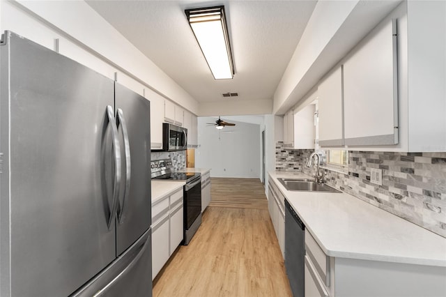 kitchen featuring appliances with stainless steel finishes, light countertops, white cabinetry, and a sink