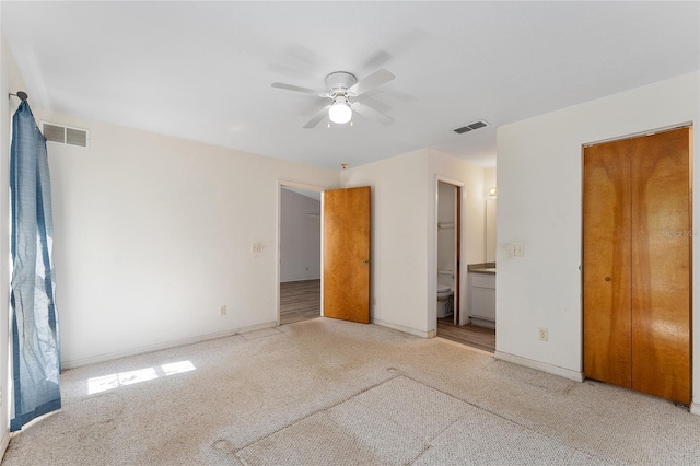 unfurnished bedroom with baseboards, visible vents, ensuite bathroom, and light colored carpet