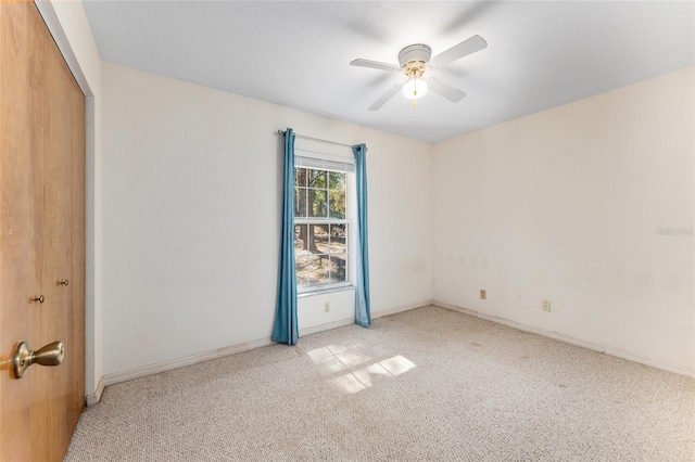 spare room featuring ceiling fan, baseboards, and light colored carpet