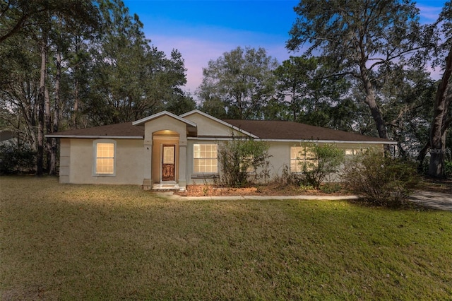 ranch-style house featuring a front lawn and stucco siding