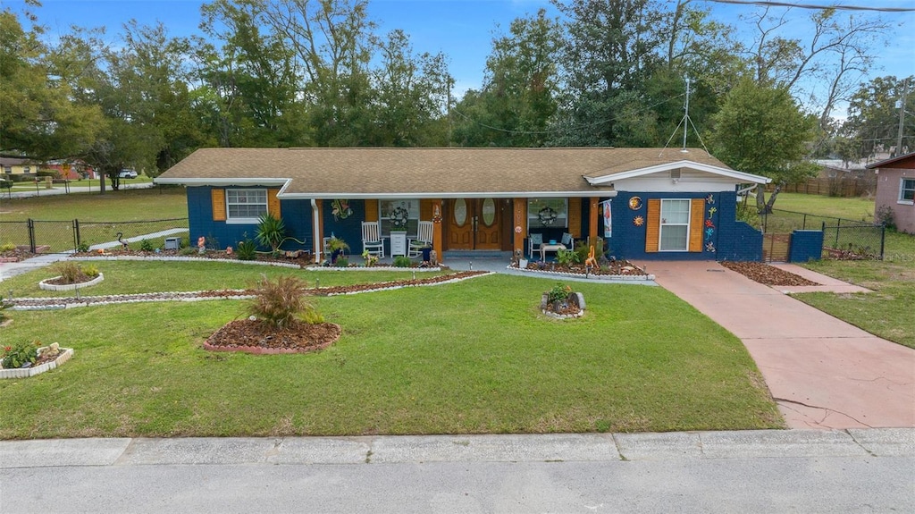 ranch-style home featuring a porch, fence, and a front lawn