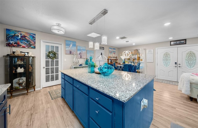 kitchen featuring light wood-style flooring, a kitchen island, hanging light fixtures, and blue cabinetry