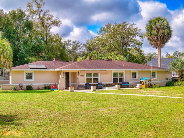 ranch-style home featuring roof mounted solar panels, a front lawn, and stucco siding