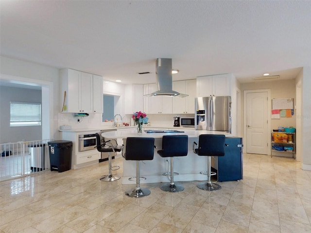 kitchen featuring stainless steel appliances, light countertops, white cabinetry, and island range hood