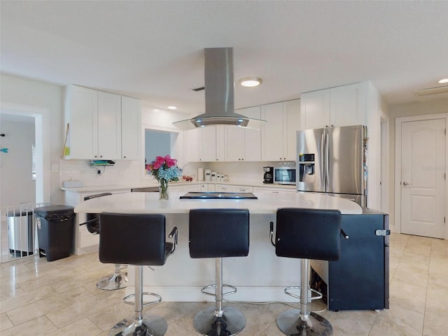 kitchen with appliances with stainless steel finishes, a center island, island exhaust hood, light countertops, and white cabinetry