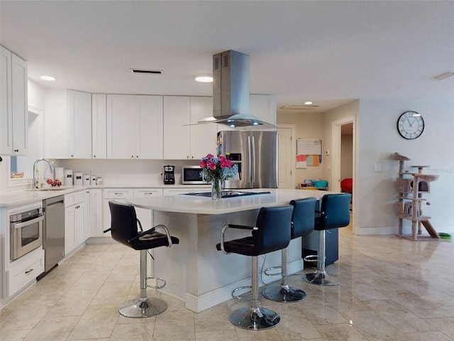 kitchen featuring island exhaust hood, stainless steel appliances, light countertops, white cabinetry, and a kitchen island