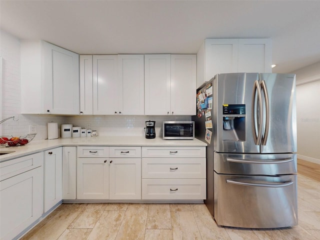 kitchen with stainless steel appliances, light countertops, backsplash, and white cabinetry