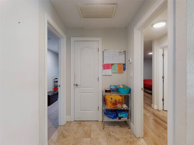 hall featuring visible vents and baseboards