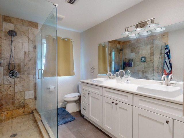 bathroom with double vanity, a stall shower, a sink, and toilet