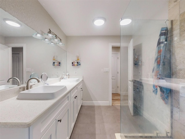 bathroom featuring double vanity, tile patterned flooring, baseboards, and a sink