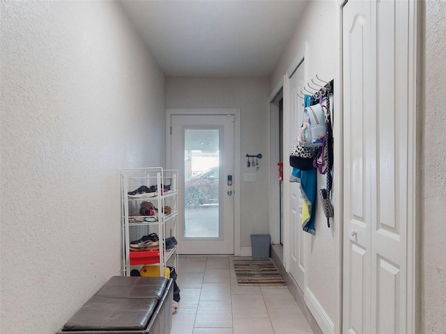 doorway featuring light tile patterned floors and a textured wall