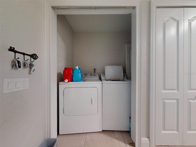 washroom with laundry area, washing machine and clothes dryer, and light tile patterned floors