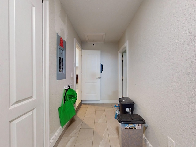 corridor featuring a textured wall, electric panel, and baseboards