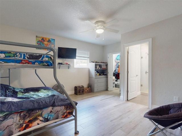 bedroom featuring light wood-type flooring, baseboards, a ceiling fan, and a textured ceiling