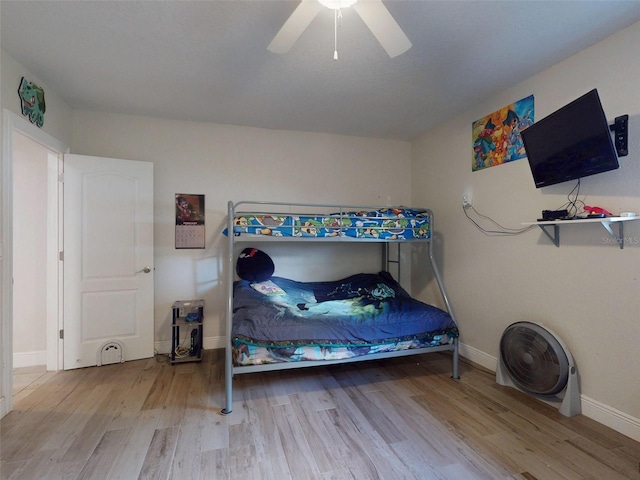 bedroom with ceiling fan, light wood-style flooring, and baseboards