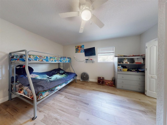 bedroom featuring a textured ceiling, baseboards, light wood-style flooring, and a ceiling fan