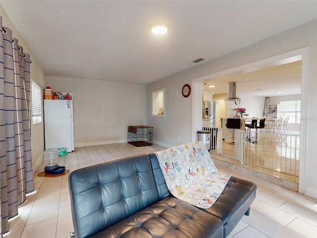 living area with light tile patterned floors, visible vents, and a healthy amount of sunlight