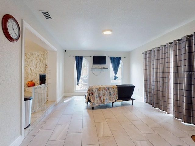 bedroom with light tile patterned floors, a textured ceiling, visible vents, and baseboards